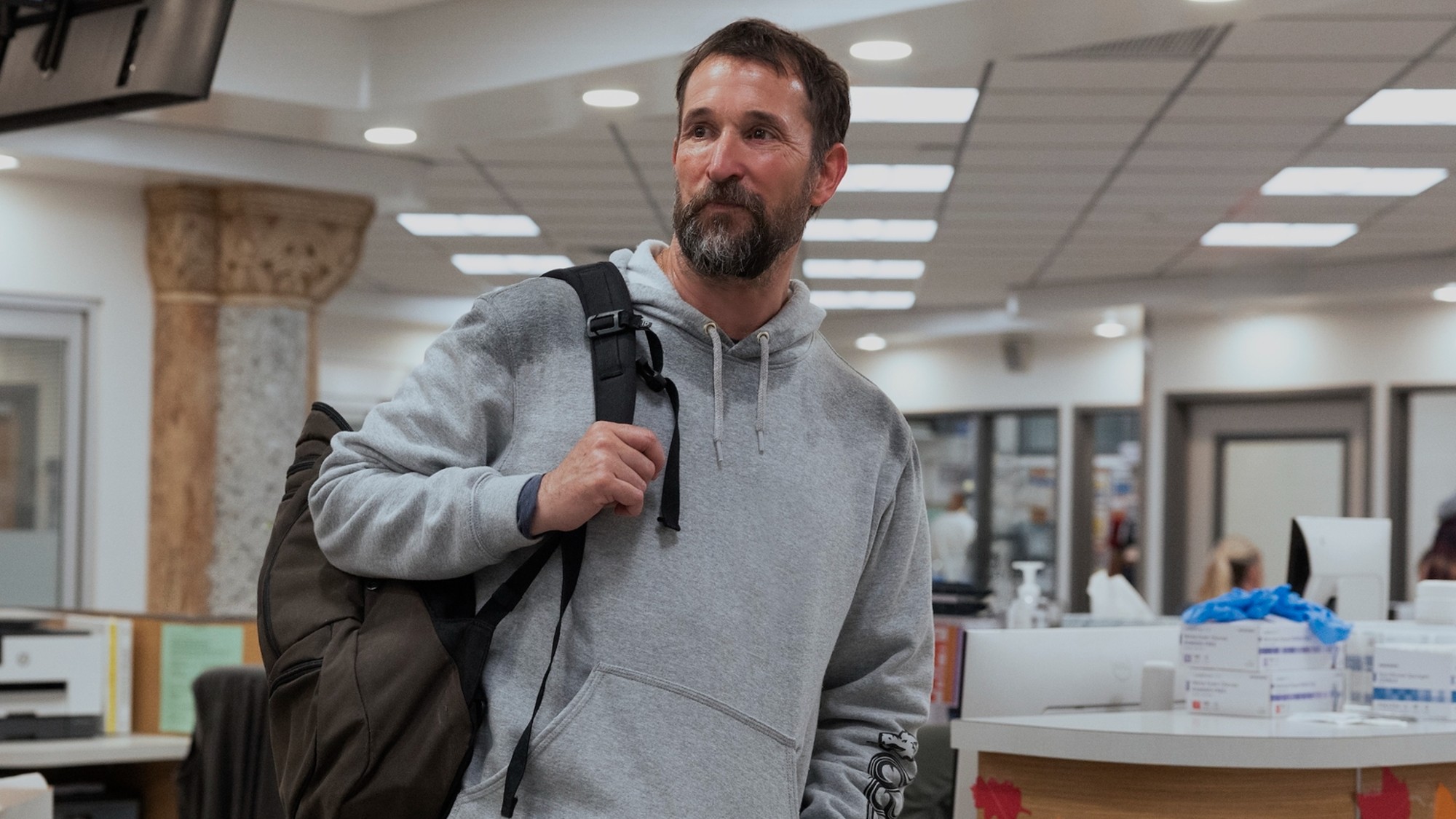 Noah Wyle in Season 3 of The Pitt holding a backpack on his shoulder. 