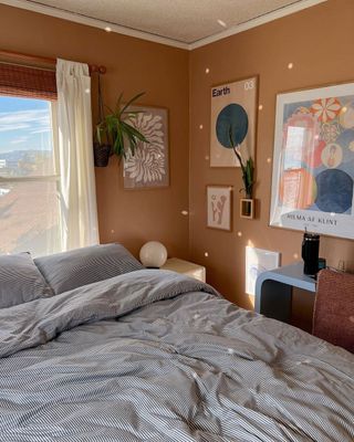 Terracotta painted small modern bedroom with pinstripe bedding in blue