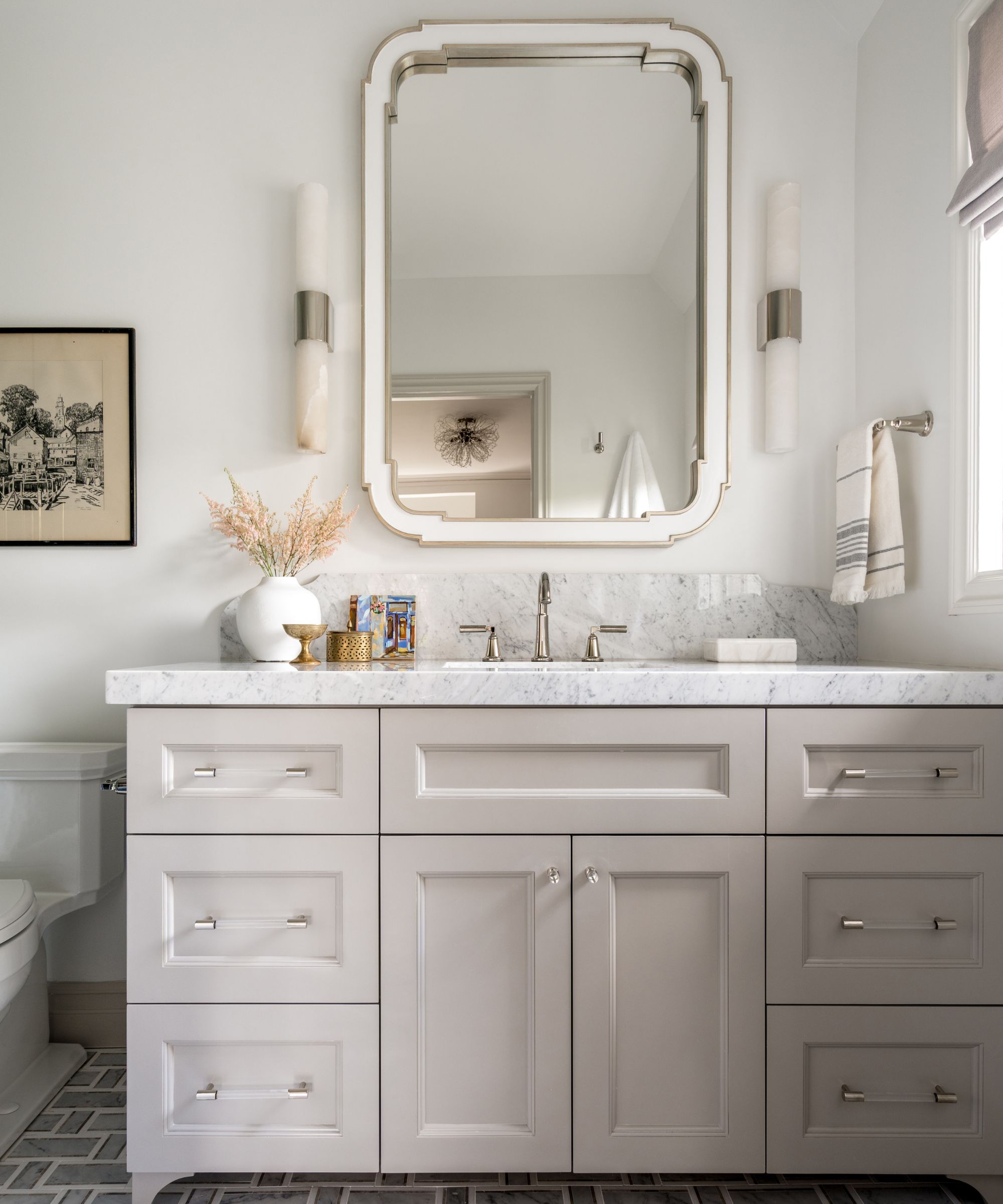 A white and cream bathroom with natural lighting and a large vanity mirror