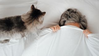 Cat trying to wake up woman in bed