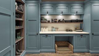 boot room with fitted blue cabinets and storage shelves, boots, shoes and space for dog bed below countertop