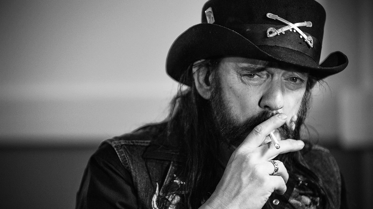 A black and white photograph of Motorhead’s Lemmy smoking a cigarette