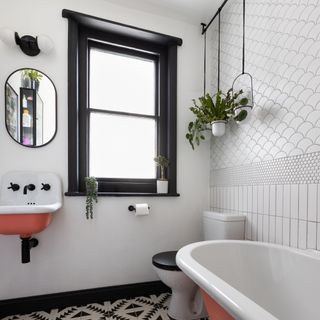White bathroom with black and white tiles, bath, toilet, window