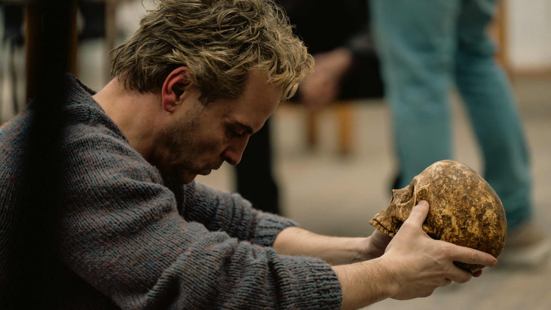 A blond man (Andrew Scott as Ian Charleson) sits in a rehearsal room while holding a weathered skull, in a still from 'Elsinore' one of the Best Drama Movies of 2026.
