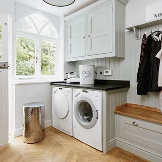 White kitchen with washing machine and tumble dryer under black granite top on wooden floor