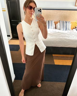 Judith wears white linen Reformation vest top and brown skirt.