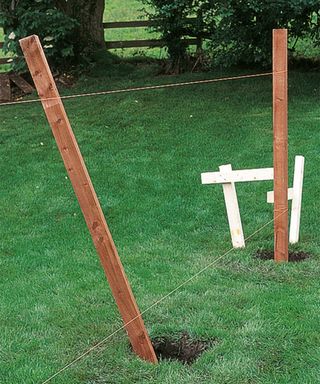 fence posts being positioned in a hole using wood to hold in place