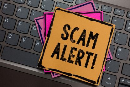 Post-it notes reading "Scam alert" on a computer keyboard