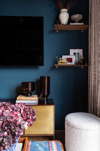 living room tv on a blue wall above a gold cabinet