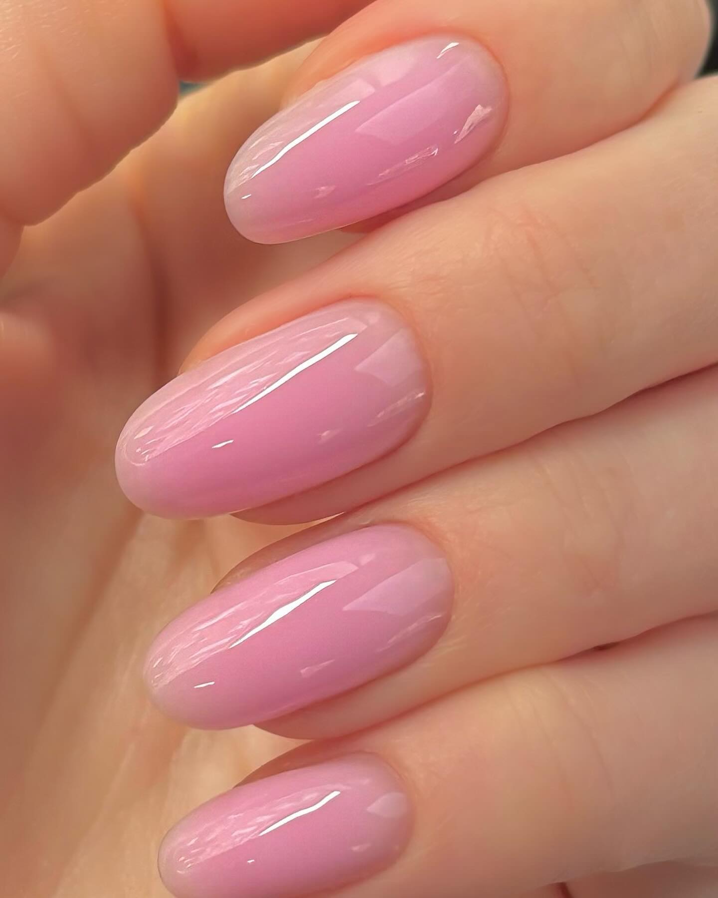 Hand with long nails painted with baby pink nail polish