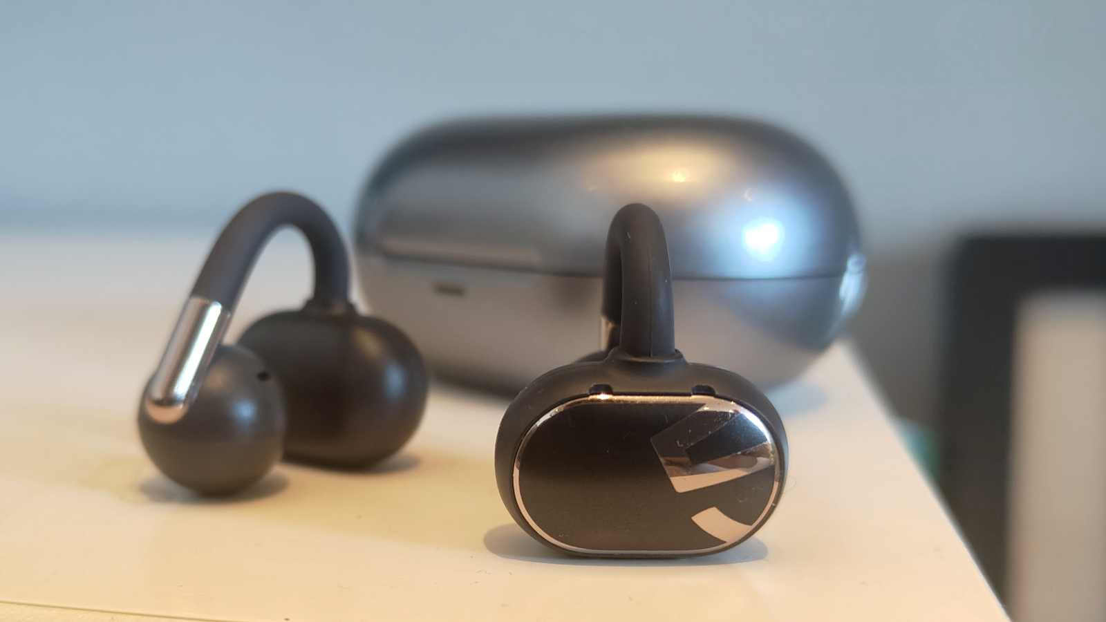 The Soundpeats Clip1 buds on a table next to the case.