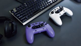 A violet and white Wireless Horipad for Steam controllers sitting on a desk in front of a keyboard.