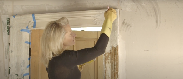 Applying wood stripper to old painted wooden door frame