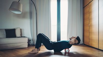 Image shows a man using a foam roller.