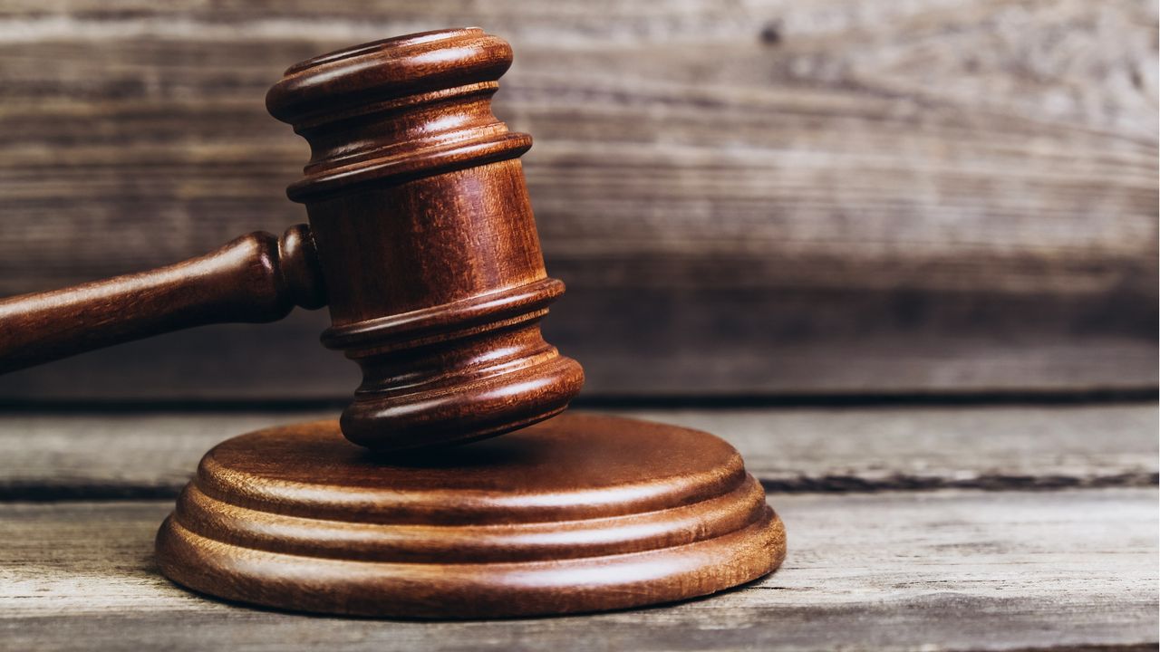 A gavel and sound block against a wooden background.