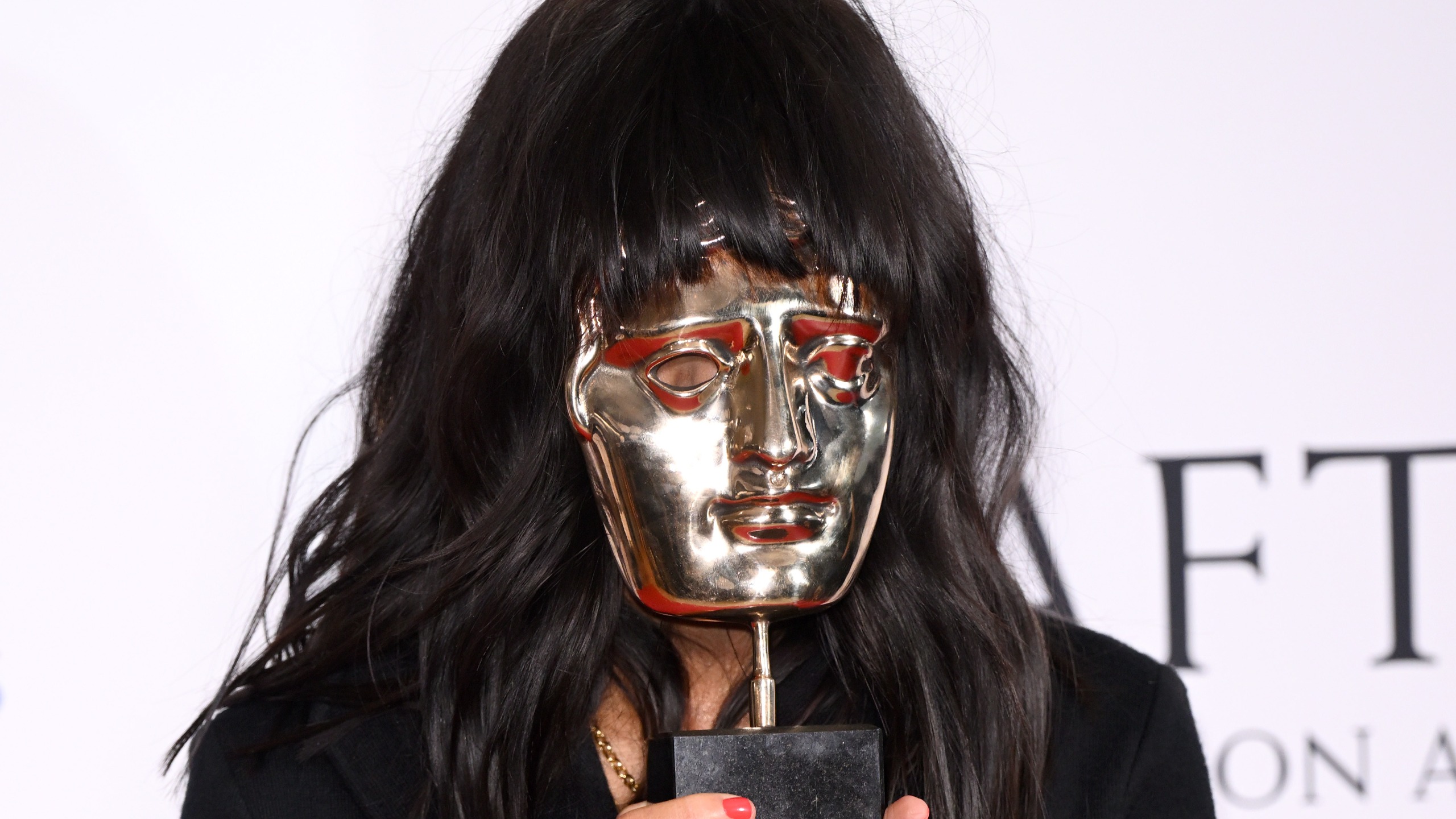 Celebrity Traitors season 2 host Claudia Winkleman holds up a silver BAFTA Television Award over her face leaving just black hair. Karwai Tang/WireImage