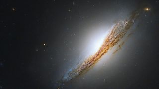 A striking orange and blue streak fills this new image from NASA's Hubble Space Telescope. Hubble’s visible and infrared capabilities captured this edge-on view of lenticular galaxy NGC 612. 