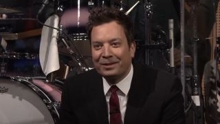 Jimmy Fallon sitting in front of Questlove's drums on The Tonight Show