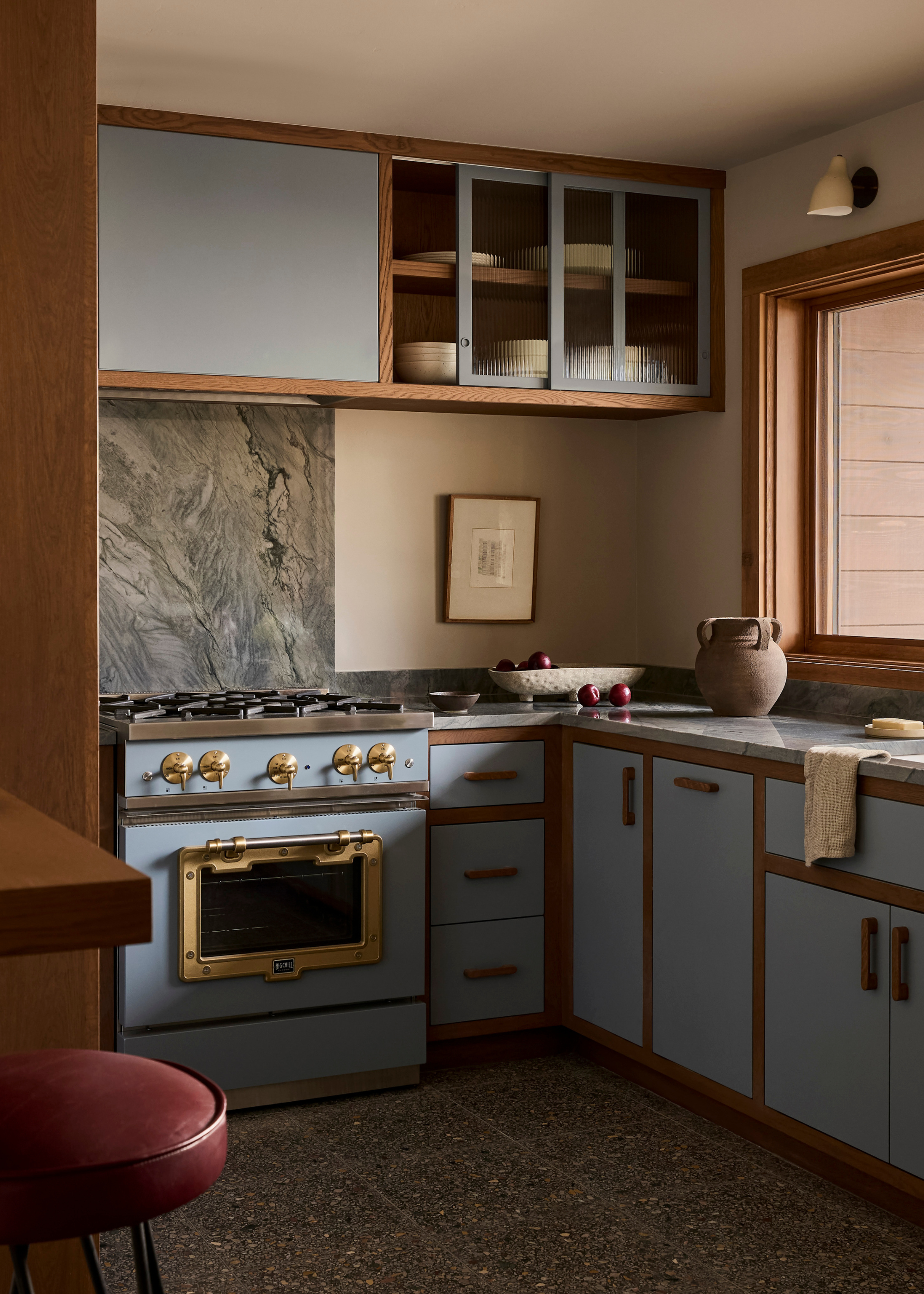 A pastel blue and natural wood finish kitchen with a matching cooker with brass fixtures