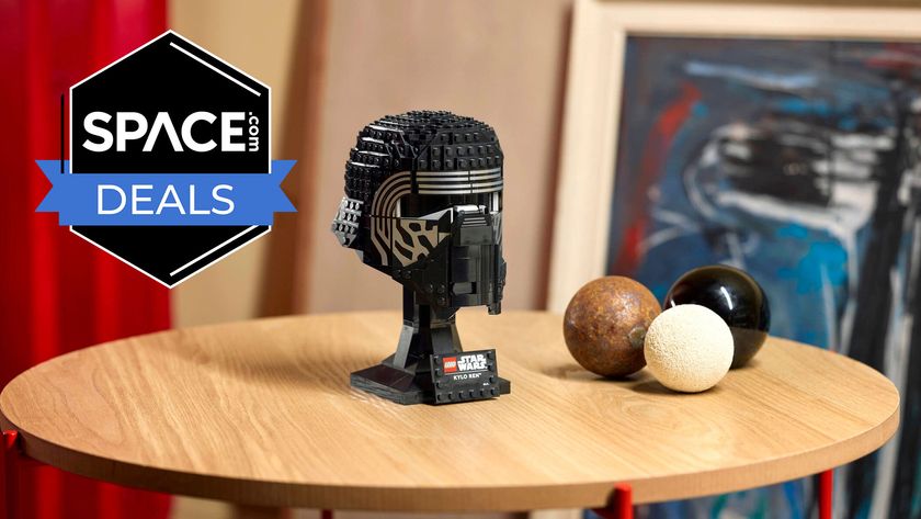 A black brick-built helmet with silver outlines around the eyes is on a display stand on a light brown wooden surface with the space.com logo in the top left corner.