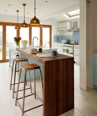 Kitchen ideas with a breakfast bar built as an extension of an island, in dark wood in a white and pale blue kitchen color scheme.