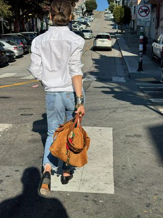 Frau trägt weiße Hemdbluse, Jeans und eine Handtasche von Parker Thatch.