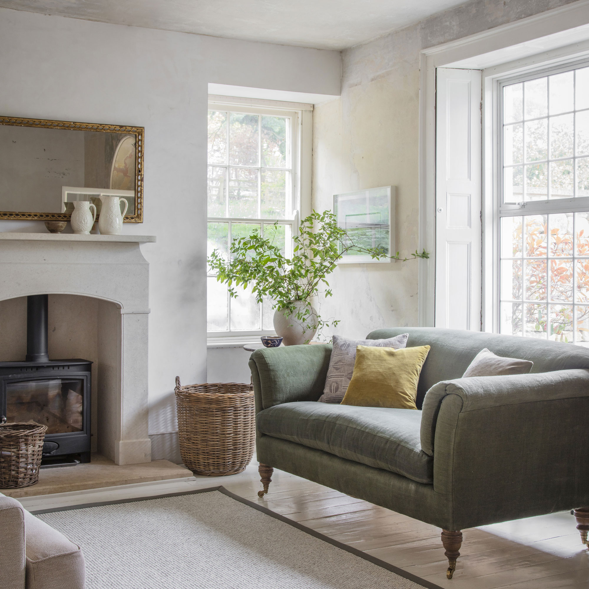 living room with sage green sofa and stone fireplace with woodburner