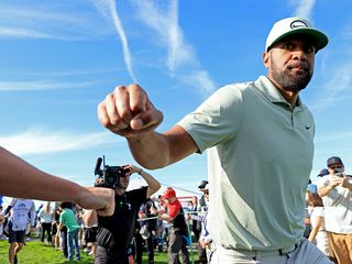 Tony Finau greeting a fan while walking on the golf course