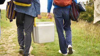 Two campers carrying a cooler