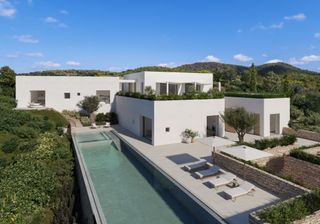 An aerial shot of a white villa with a long pool