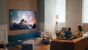 LG G2 OLED TV mounted on living room wall with family watching