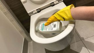 Toilet bowl cleaner being applied under the rim of a toilet bowl