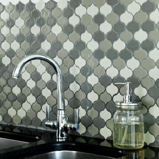 kitchen with hand wash jar and sink tap with patterned tiles