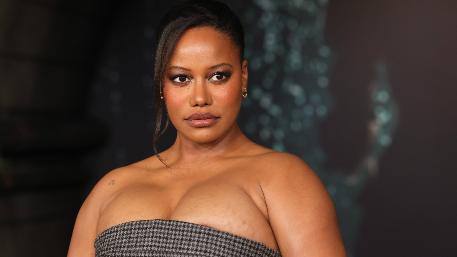a black woman with dark hair wearing a strapless, checkered gown at a red carpet event