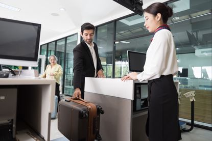 Woman airline ground staff helping traveler with check in at terminal counter