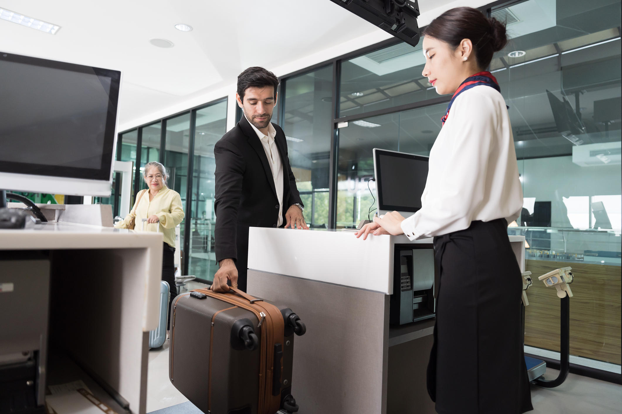 Woman airline ground staff helping traveler with check in at terminal counter