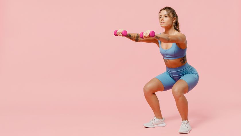 a woman doing a squat while holding two light dumbbells in her hands