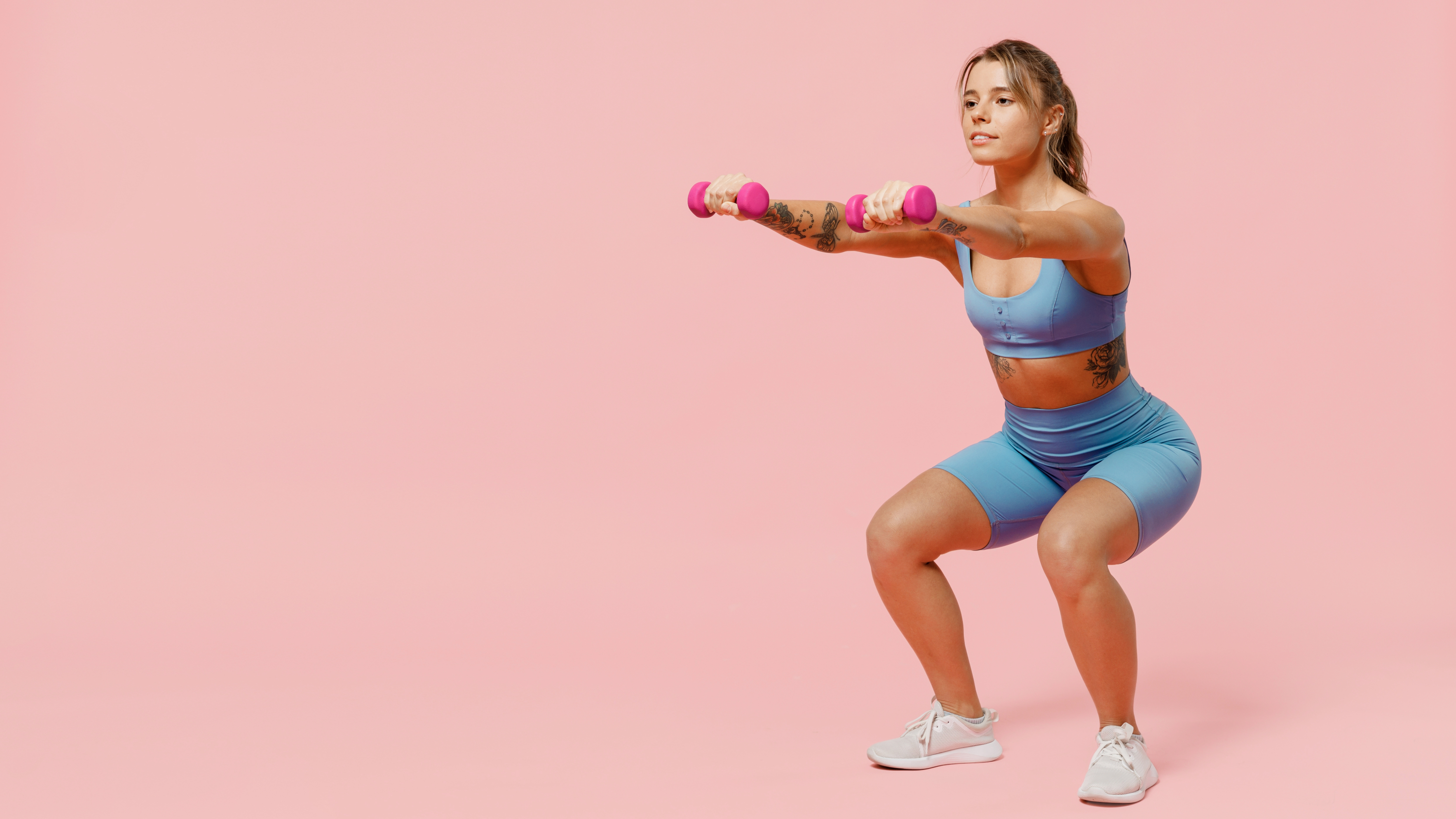 a woman doing a squat while holding two light dumbbells in her hands