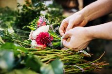 A close-up of a florist carefully preparing different flowers for a bouquet.