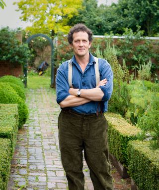 Monty Don standing with his arms crossed in a garden