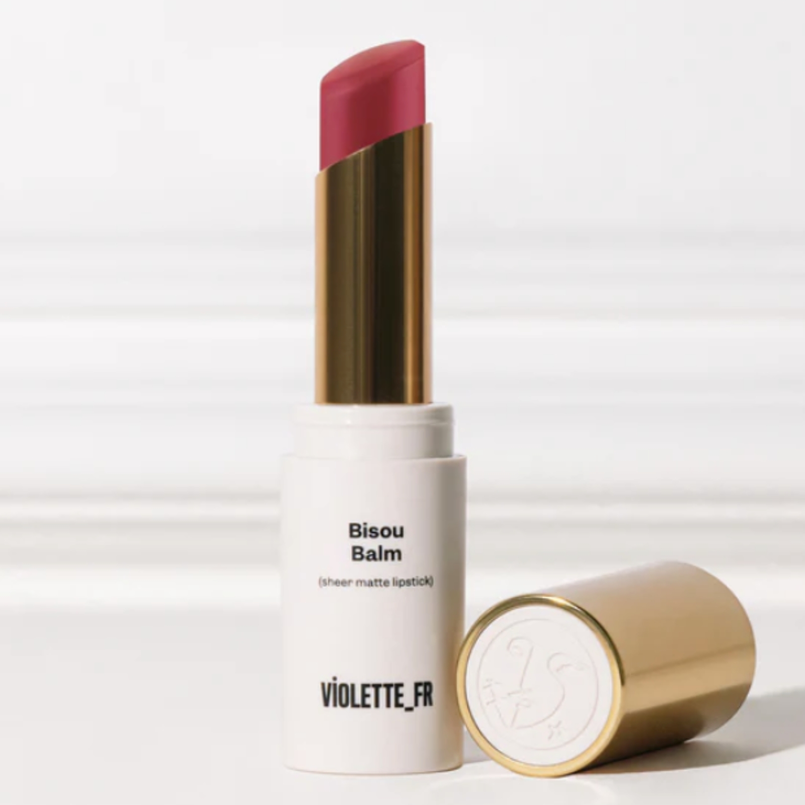 A product shot of the Violette_Fr Bisou Balm in Rose Latte, on a white and grey background