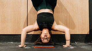 Woman performing handstand push-up with pad under her head