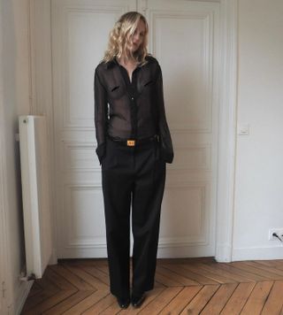 Elly McGaw wearing a black sheer button-down blouse and black trousers.