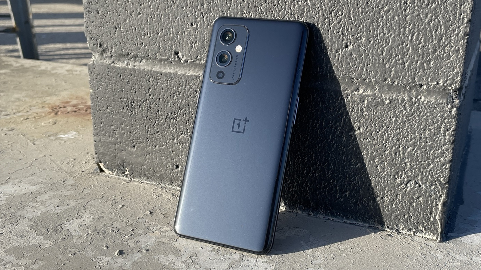 A OnePlus 9 from the back, resting against a wall