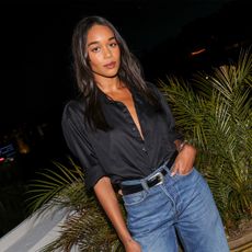 Laura Harrier at the Frame x Amelia Gray Dinner held at Chateau Marmont on April 4, 2024 in Los Angeles, California wearing a black button-down shirt, blue jeans, and a black and silver Western belt.