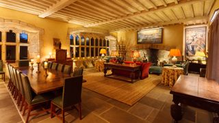 large open plan living and dining room with tiled floor, wooden beamed ceiling, brick fireplace, furniture and a variety of lighting 