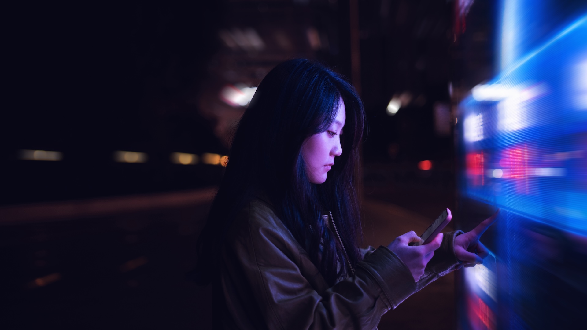 a woman uses her phone surrounding by bright flashing lights