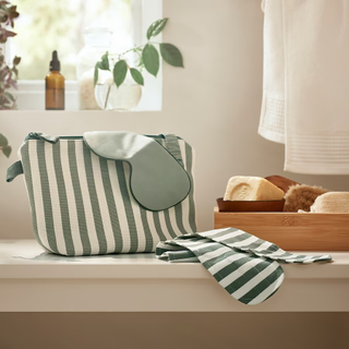 A green and white striped wash bag on a bathroom counter