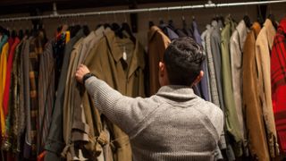 man looking through clothes rail in vintage shop