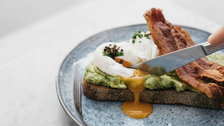 Bacon rasher increases dementia, Knife cutting through avocado toast with egg and bacon